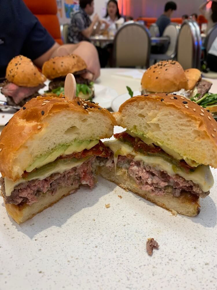 다져딘 패티와 치즈, 할라피뇨, 선드라이즈 토마토가 보이는 햄버거 단면