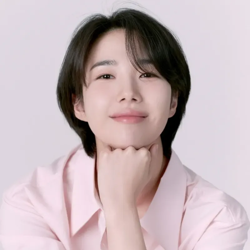 분홍색 배경에 분홍색 셔츠를 입고 미소짓는 오랫동안 당신을 기다렸습니다의 양희주