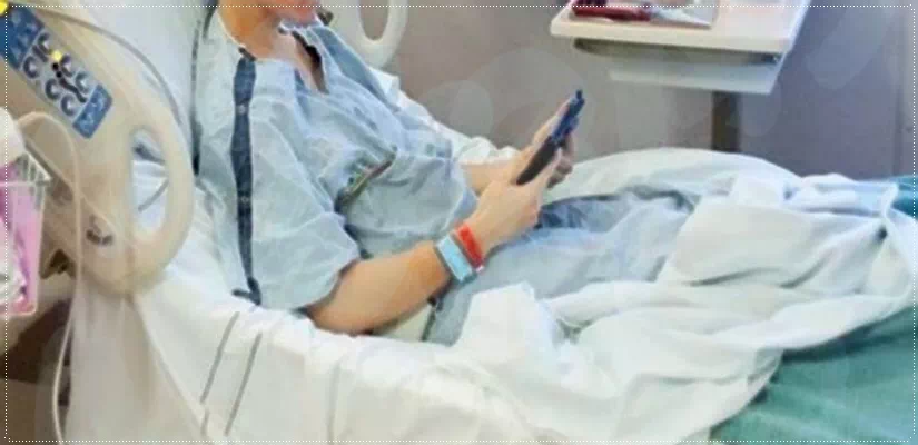 병원침대에 앉아 폰을보는 환자