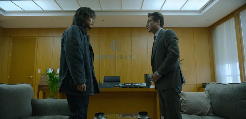 어느 은행의 점장실 안에서 VIP 고객이지만 노숙자 차림을 한 성기훈을 극진히 대접하고 있는 은행 점장