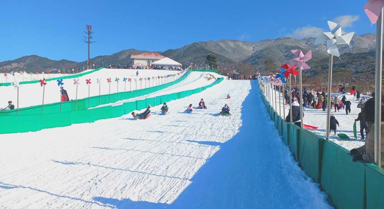 두 개의 슬로프가 나란히 놓인 눈썰매장 전경과 썰매를 들고 올라가는 아이들이다. [ⓒ남원시청]
