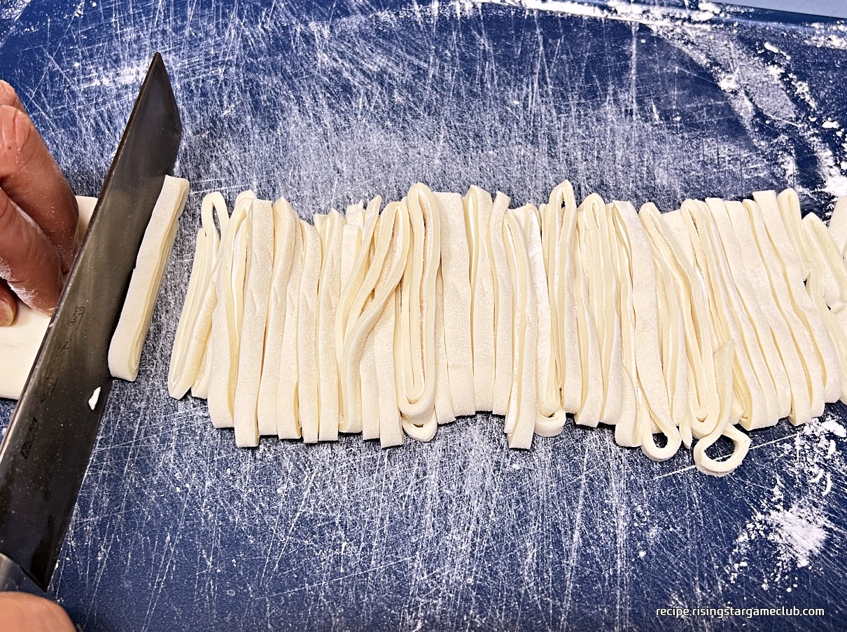 밀대로 편 숙성된 바지락 칼국수의 반죽을 말아서 얇게 써는 사진
