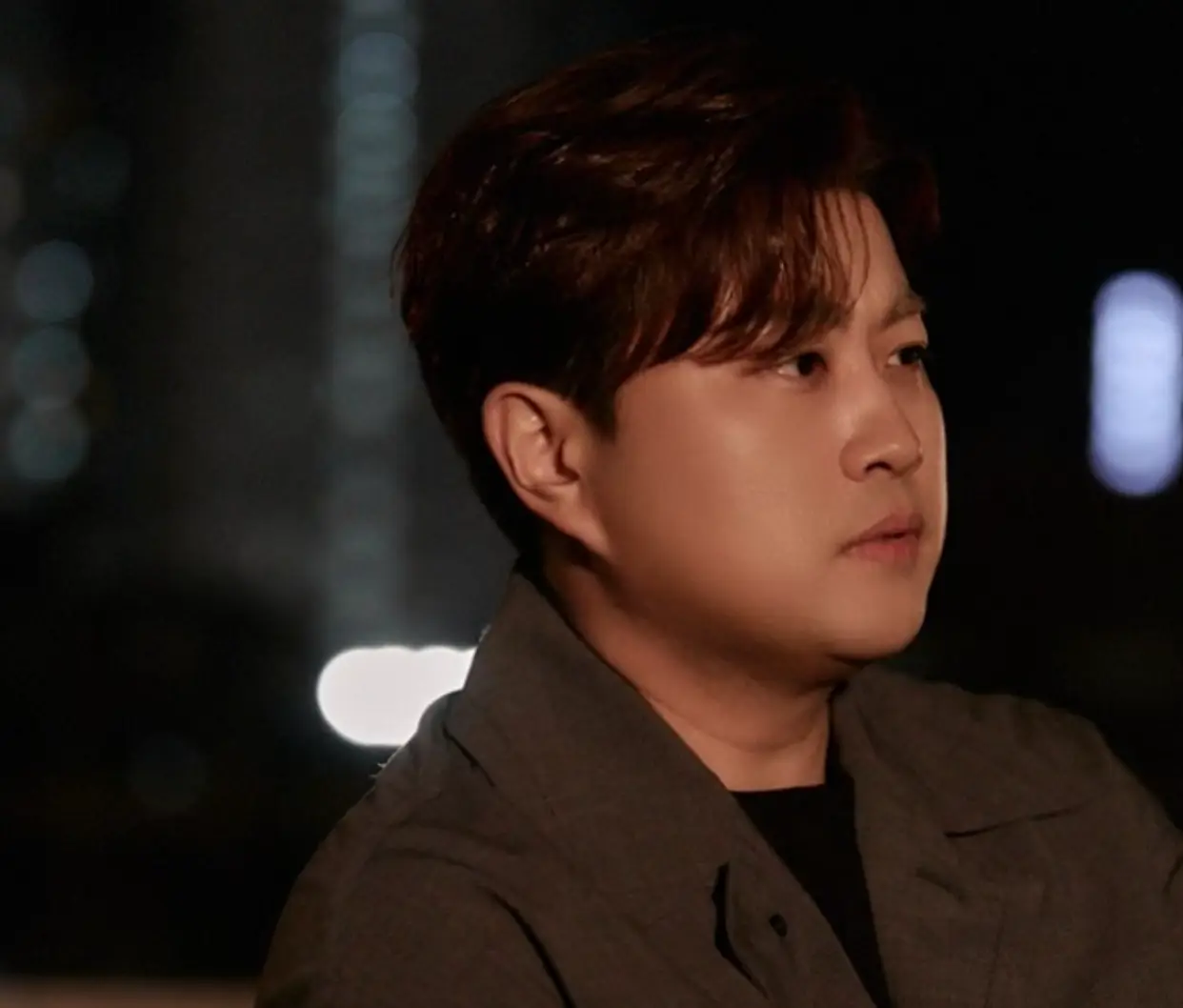 어두운 밤 갈색 자켓을 입은 김호중의 옆모습