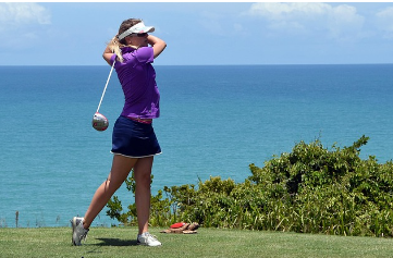 한 여성이 바다를 배경으로 골프를 치고 있다.