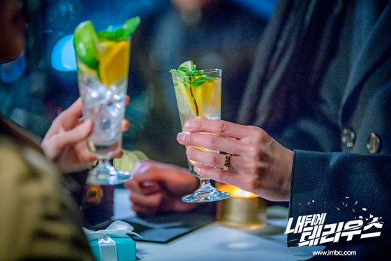 테이블 위에서 두 인물이 음료 잔을 들고 있는 손의 근접 사진
