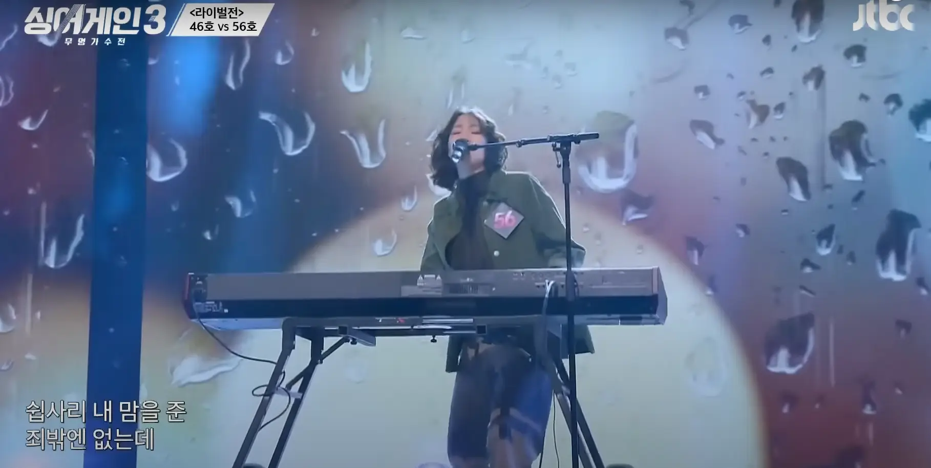 싱어게인 3- 초록색 자켓을 입고 곱슬단발머리로 스탠딩마이크앞에서 전자건반을 치며 노래하는 56호 상반신