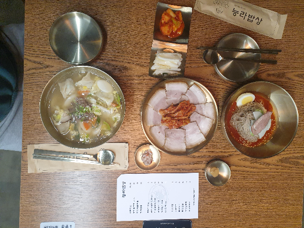 테이블 위에 평양만둣국(왼쪽), 돼지고기편육(중간), 비빔냉면(오른쪽)이 차례대로 놓여있다.