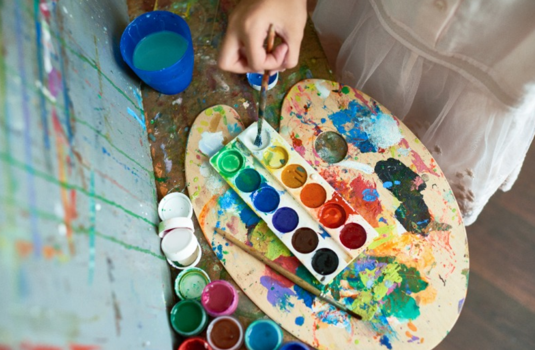 한 화가가 팔레트에 물감을 묻히고 있다.