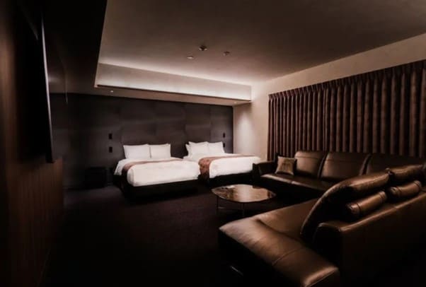 실내에 침대 2개와 쇼파가 놓여져 있다. 전반적으로 어두운 색감을 보이는 실내