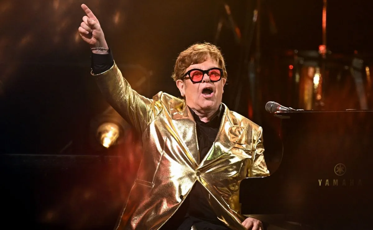 피아노 앞에서 금색 자켓을 입고 있는 엘튼 존