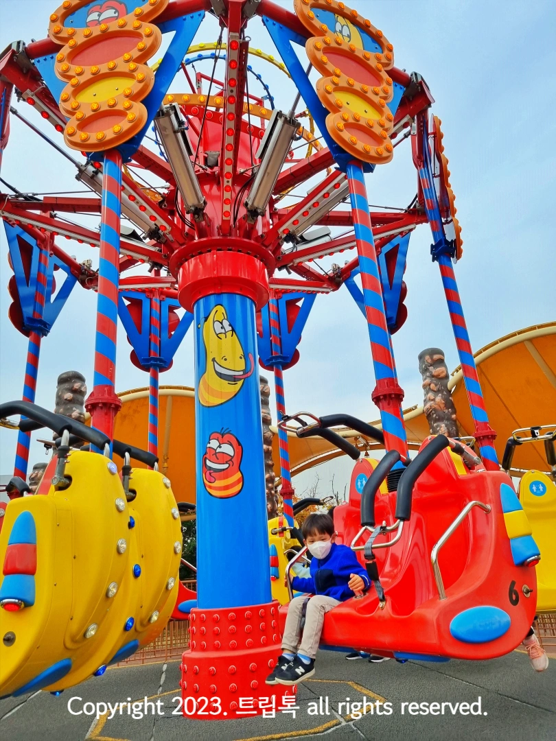 노란 라바가 그려진 그네모양 놀이기구를 탄 아이