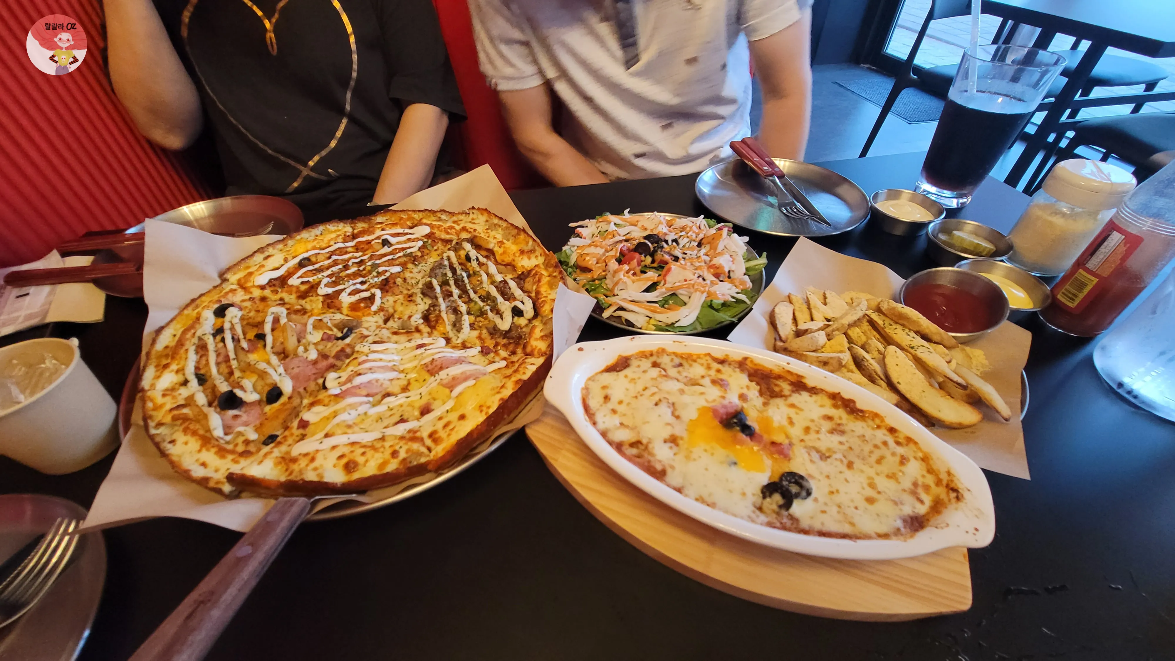 피자, 샐러드, 치즈스파게티, 웨지감자, 음료가 함께 차려진 식탁