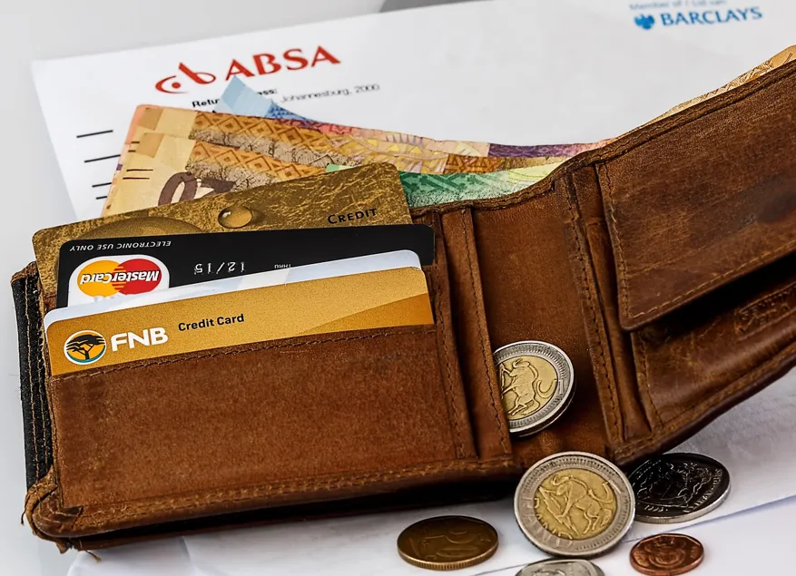 갈색지갑에-카트-4개가-꽂혀-있고-동전-5개정도-지갑에서-흘려-있는-모습-지갑-뒤에-지폐가-몇장-있음