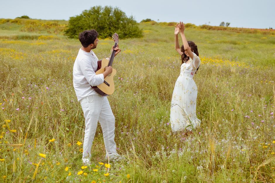 A couple in love enjoying music in a sunny field full of wildflowers.