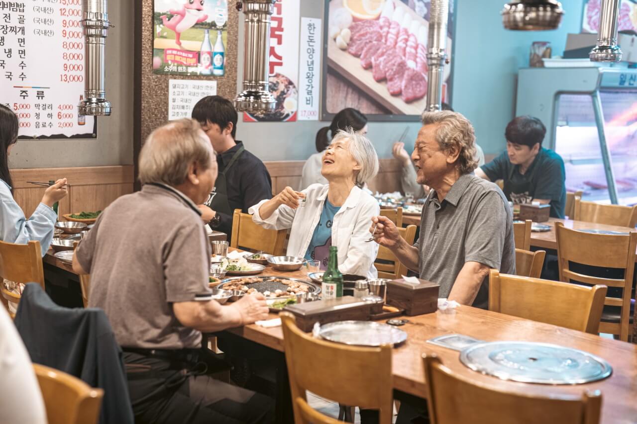 고기집 테이블에 앉아 웃으며 이야기 하는 세 명의 노인들