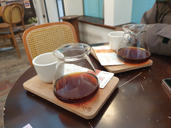 테이블 위에 두 개의 커피가 올려져 있다. 커피 서버와 컵이 각각 나와있다.