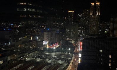 오사카의 야경, 건물들의 불이 밝혀져 있고 주차장에 차들이 주차되어 있는 모습이 보인다.