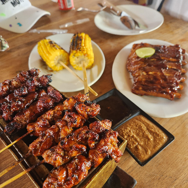 폭립, 꼬치, 구운 옥수수가 놓여있다. 식탁에는 모자와 선글라스도 보인다.