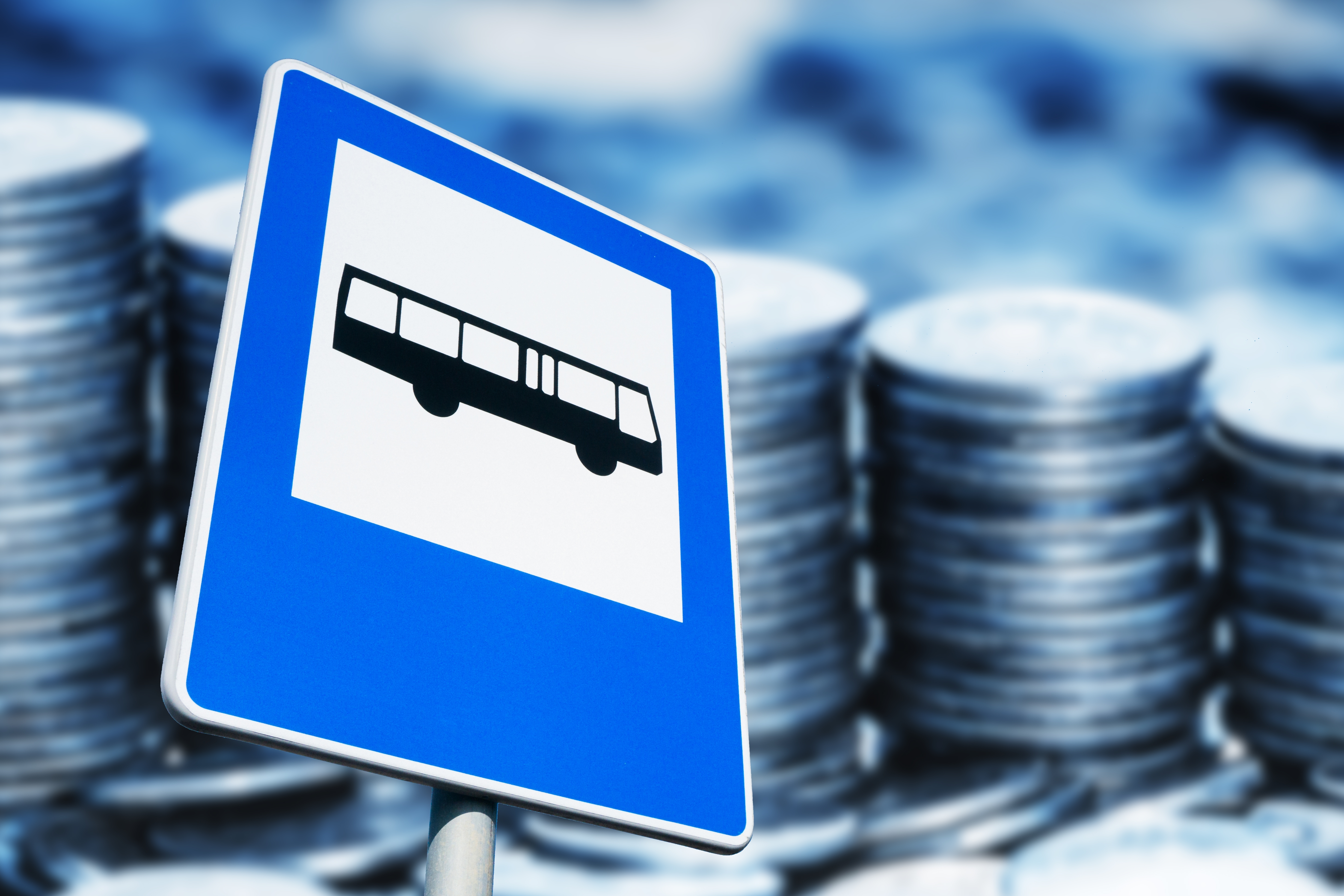 버스 정류장 표지판과 쌓인 동전들｜청년 교통비 절감과 대중교통 지원을 상징하는 이미지