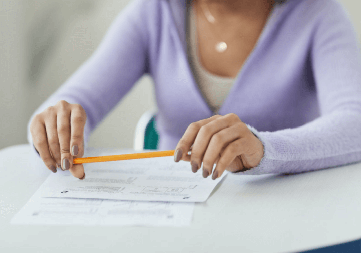 시험을 치기 위해 책상에 앉아서 연필을 쥐고 있는 사람