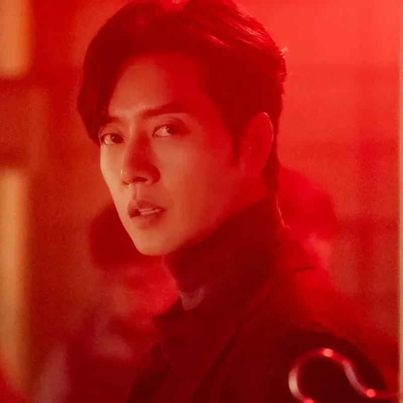 빨간 조명을 배경으로 검은 정장을 입고 있는 국민사형투표의 김무찬