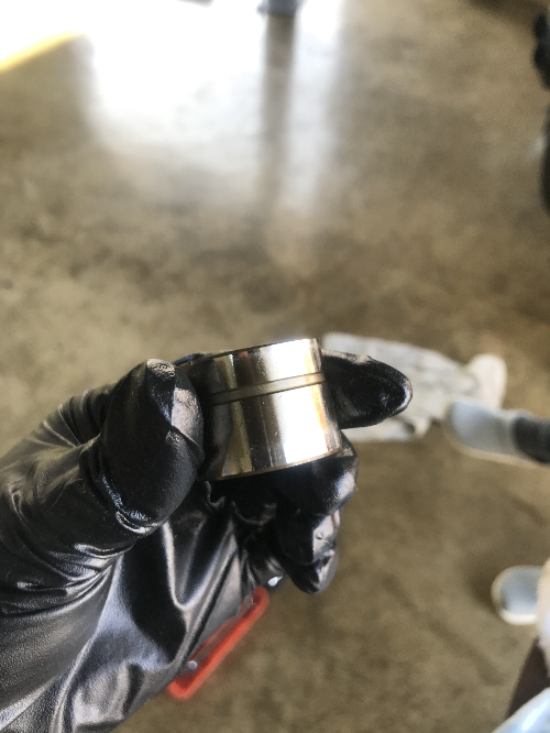 정비사가 손에 들고 있는 BMW 유압태핏 구품의 측면 모습&amp;#44; 오염과 마모 흔적이 보이는 상태