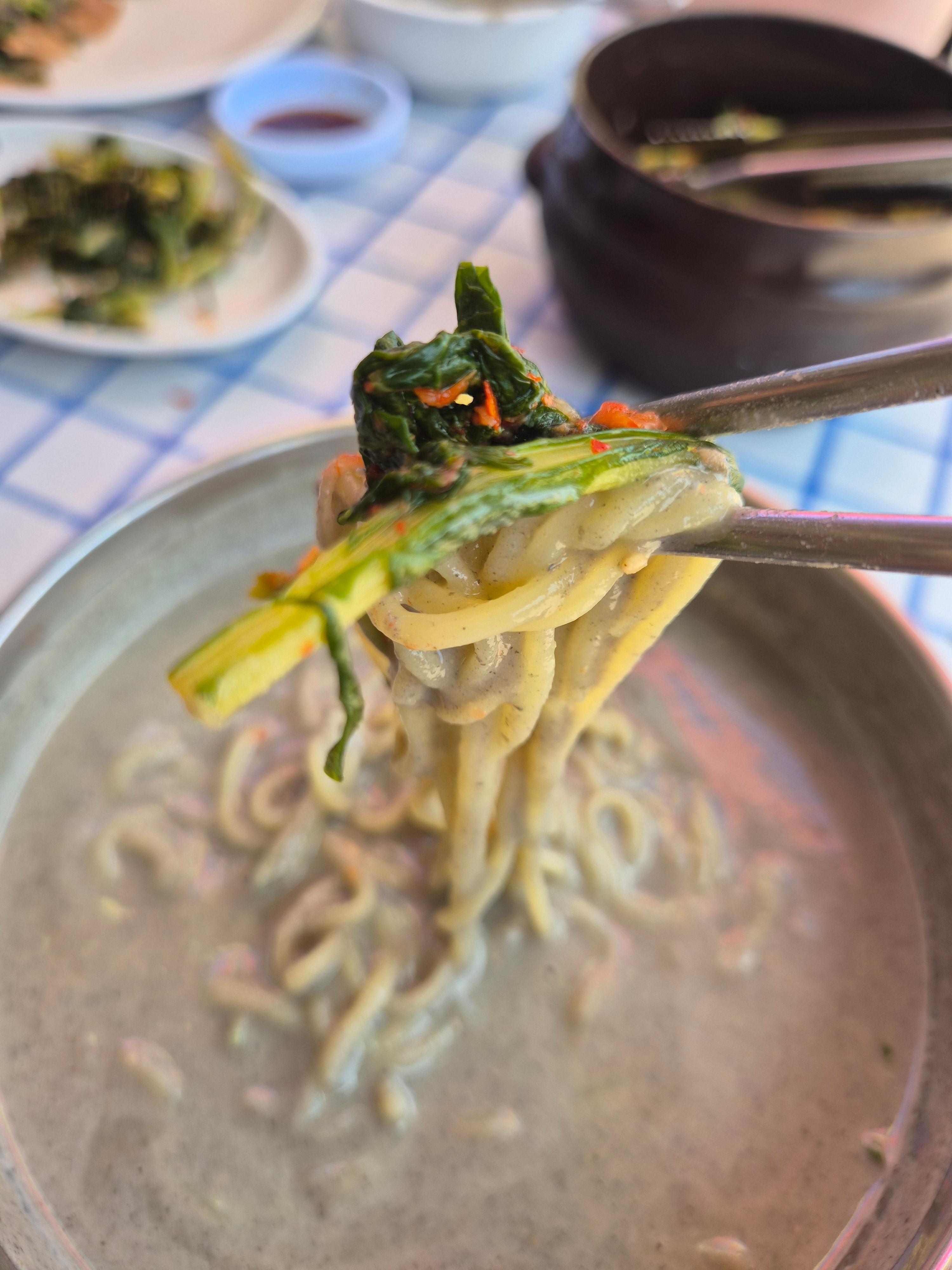 진한 콩국수 면에 열무김치를 곁들여 먹는 장면