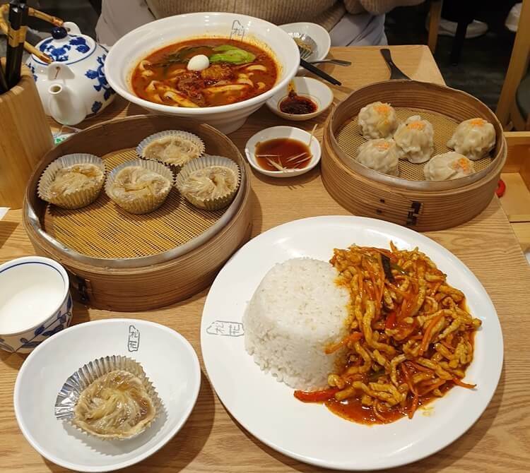 건대입구역-송화산시도삭면-소룡포-쇼마이-어향육슬덮밥-중국식간장과-차가-테이블에-올려져있다