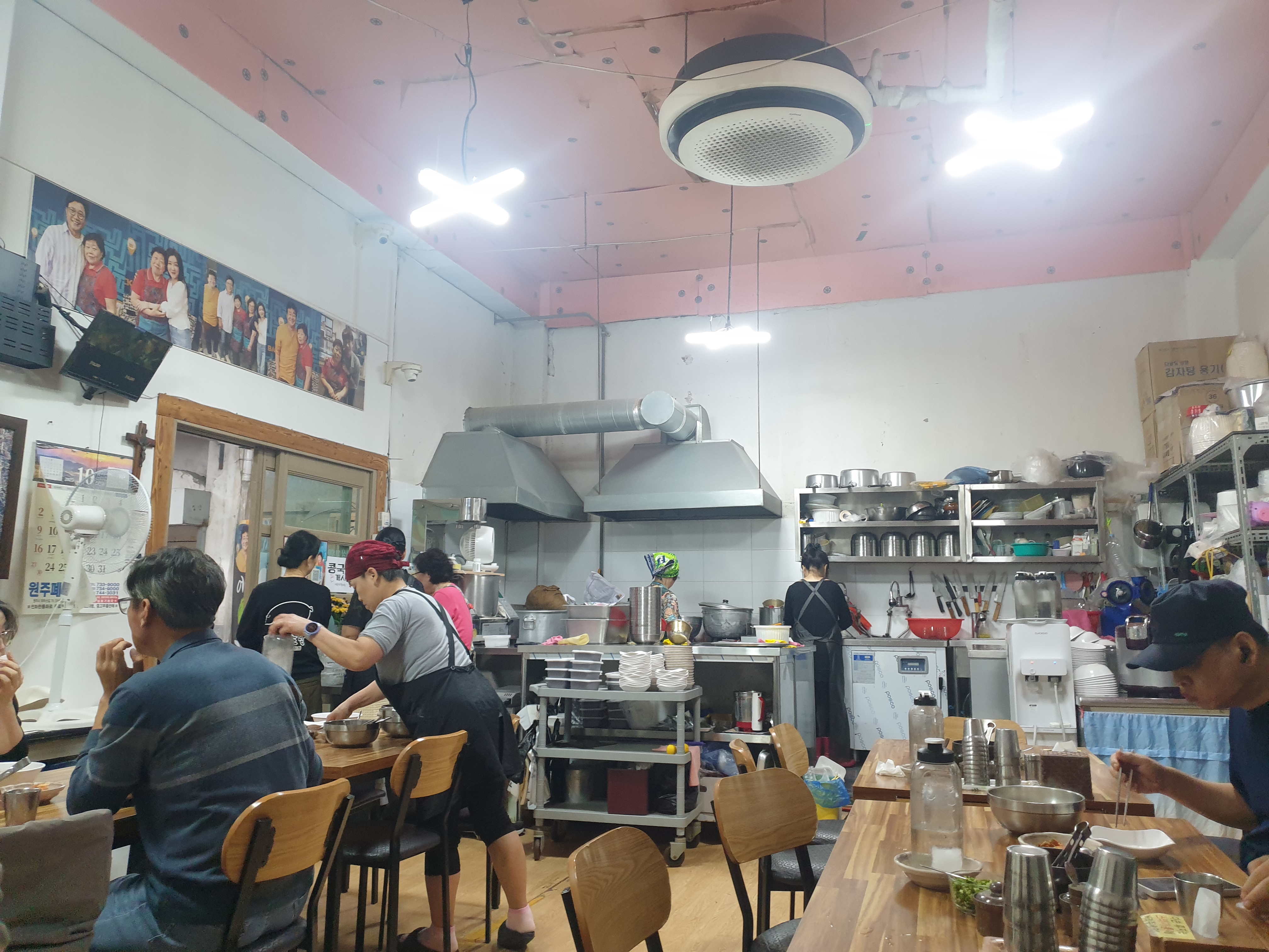 핑크 천장과 우드 테이블 내부, 왼쪽 벽 상단에는 골목식당 출연 사진이 있다.