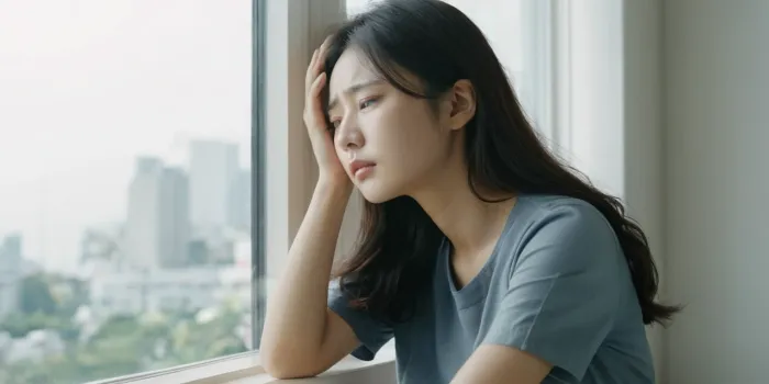 창가에 앉아 머리를 짚으며 피곤해하는 장면