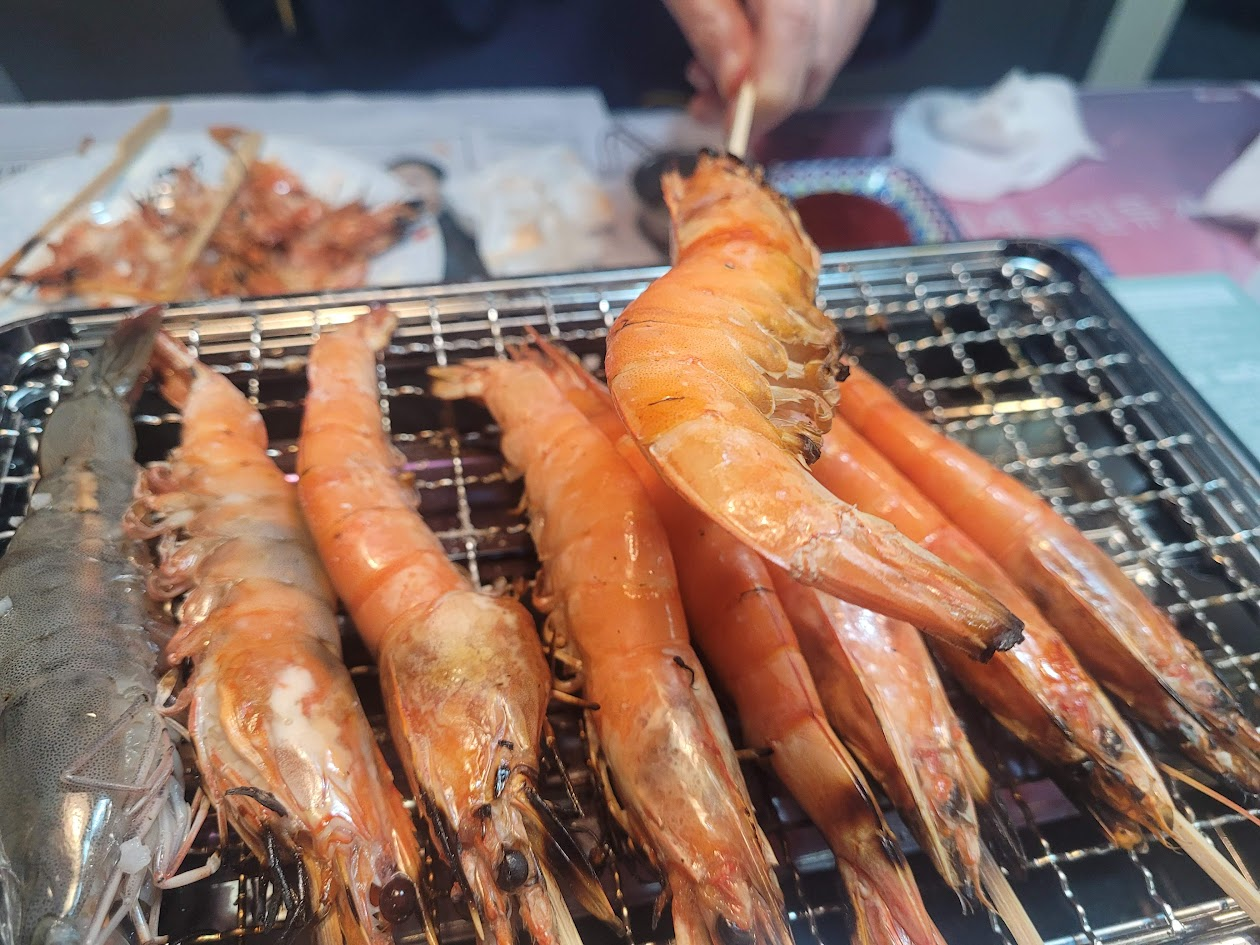 잘 구워진 새우꼬치를 하나 들고 있는 모습