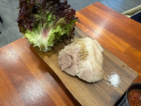 도마 위에 얇게 썰어 담아낸 돔베고기 소 사이즈 사진. 담백한 제주식 수육이 접시에 가지런히 올려져 있다.