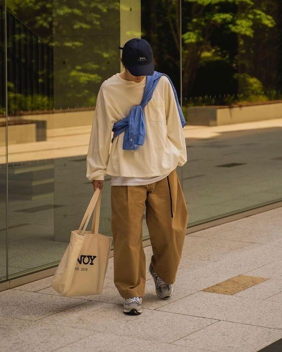 위 사진과 비슷한 시티보이룩이지만&#44; 셔츠를 어깨에 걸치지 않고&#44; 크로스백처럼 가슴 앞에서 묶어서 코디한 사진이다.
블랙 컬러 볼캡&#44; 화이트 컬러 긴팔티&#44; 진베이지 컬러 면바지에 그레이 컬러 신발을 착용한 코디에 크로스백 형태로 소라색 셔츠를 매치해주었다.