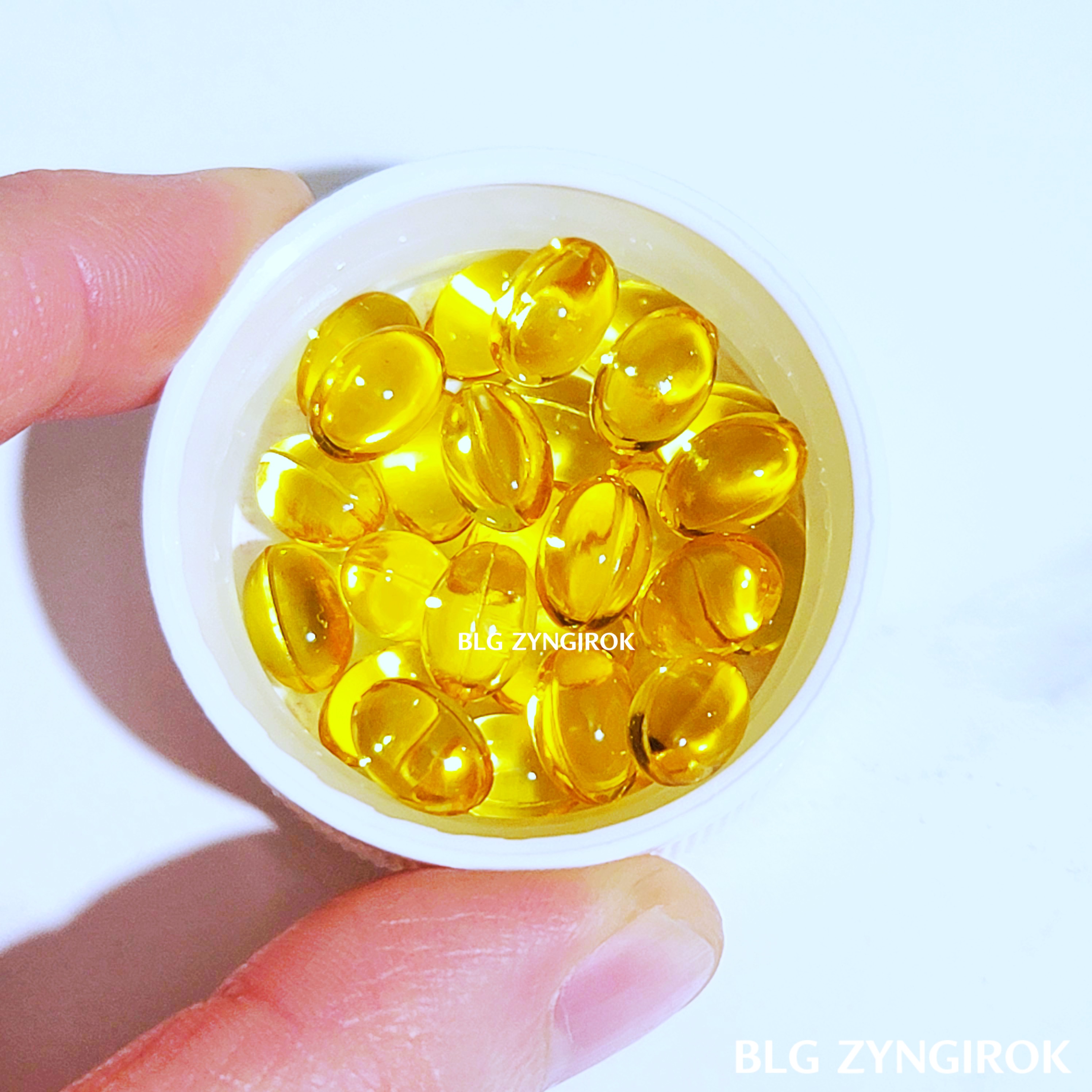 나우-비타민-d의-캡슐이-담긴-뚜껑을-손으로-잡고있다.-캡슐이-엄지-손톱의-절반크기인것을-알수있다.