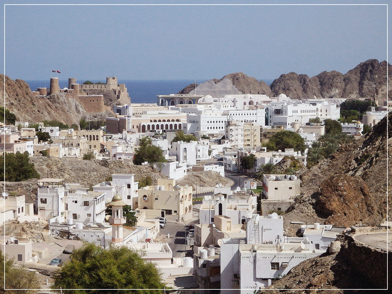 무스카트의 바위지형에 가득한 하얀 건물들. 멀리 바다가 보인다.