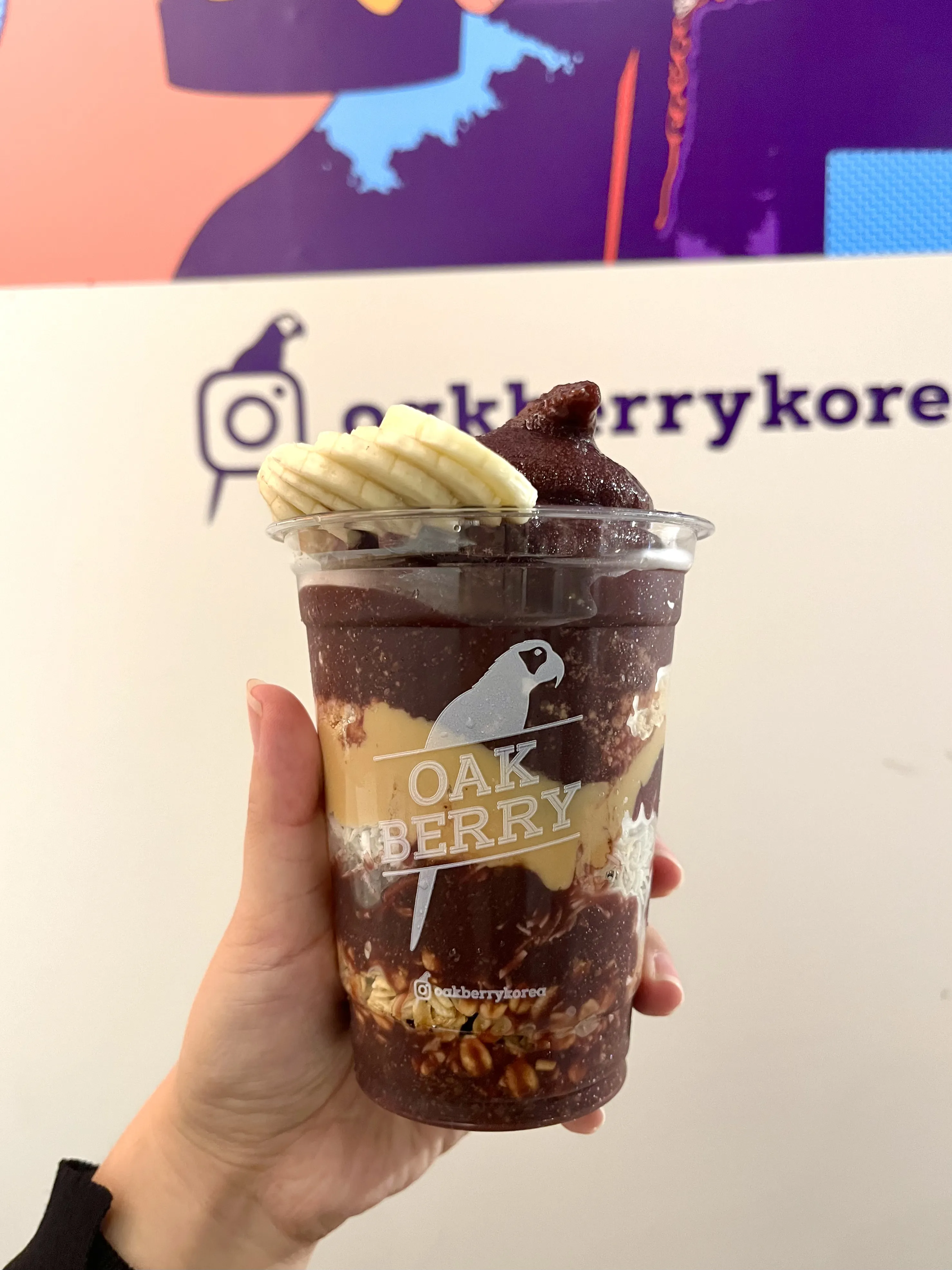 아사이-베리와-바나나-토핑이-담긴-컵을-들고있는-손