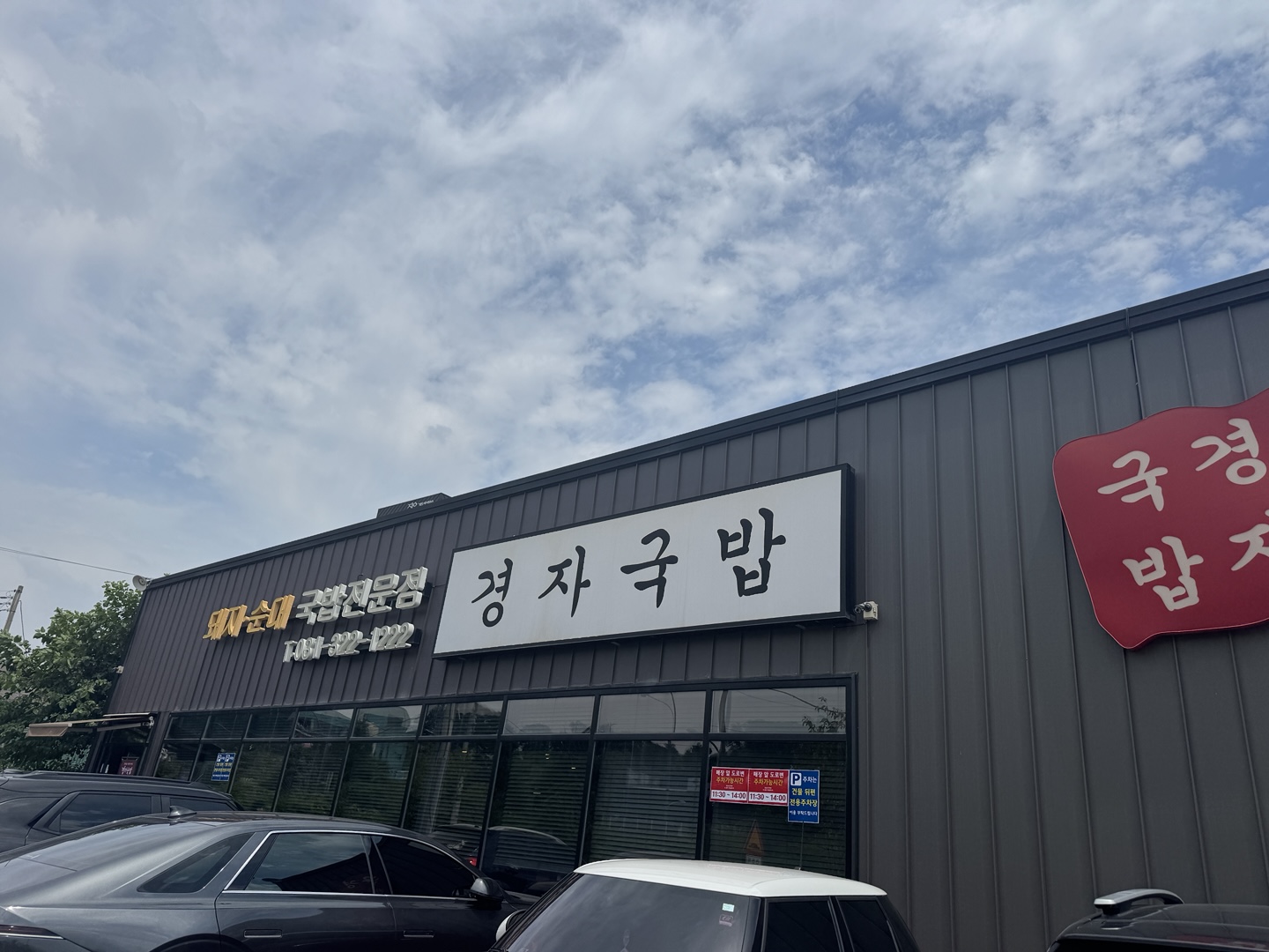 경기 용인시청 근처 경자국밥 본점 외관. 큼직한 간판과 깔끔한 건물 외벽이 눈에 띄며, 가게 앞에는 주차된 차량들이 보인다.