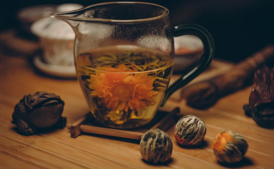 컵에 꽃잎과 약재가 담긴 차 한잔이 있다.