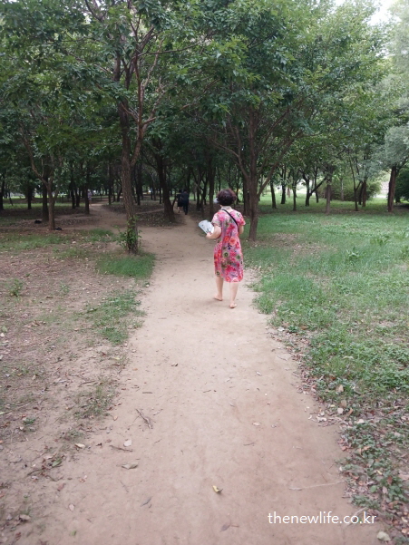 광나루 한강공원의 숲속- 서울 맨발 걷기 좋은 장소에서 맨발로 걷는 중년 여성