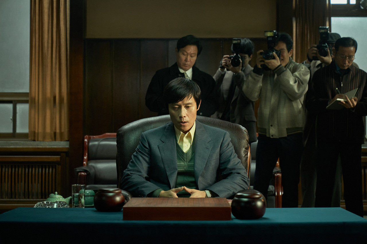 영화 승부의 주인공 조훈현이 대국을 앞두고 있는 모습과 뒷편의 기자들이 사진을 찍고 있는 모습