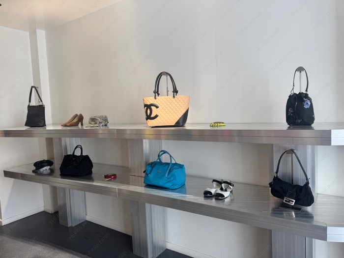 Curated vintage designer bags including Chanel and Prada on metallic shelves at Nuovo Paris ❘ Sacs de créateurs vintage chez Nuovo
