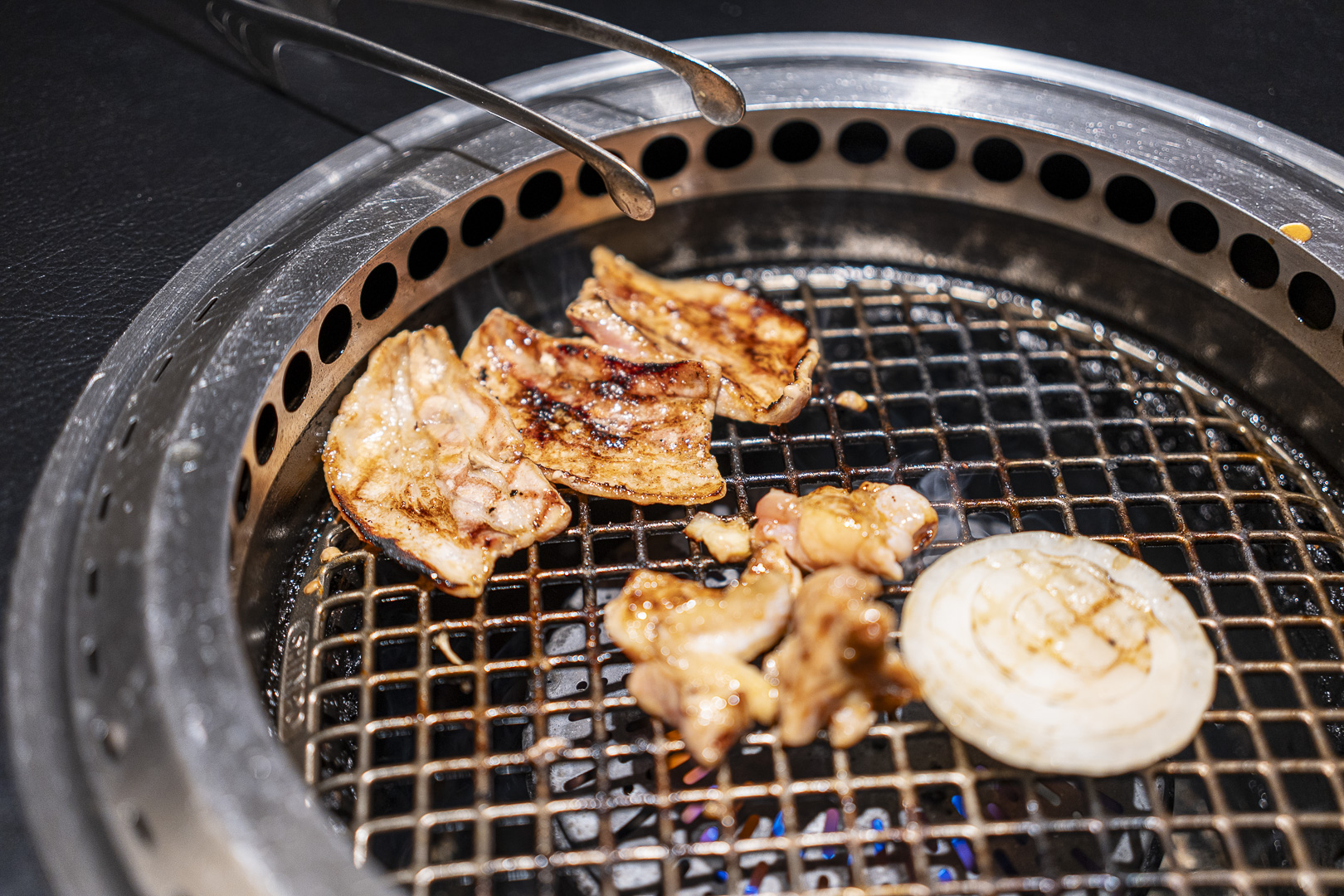 Yakiniku R29: Meat and onions grilling on a wire rack.