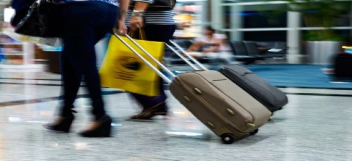 공항 실내에서 두 명의 승객이 각자 캐리어를 끌고 출국 수속을 준비하는 모습.