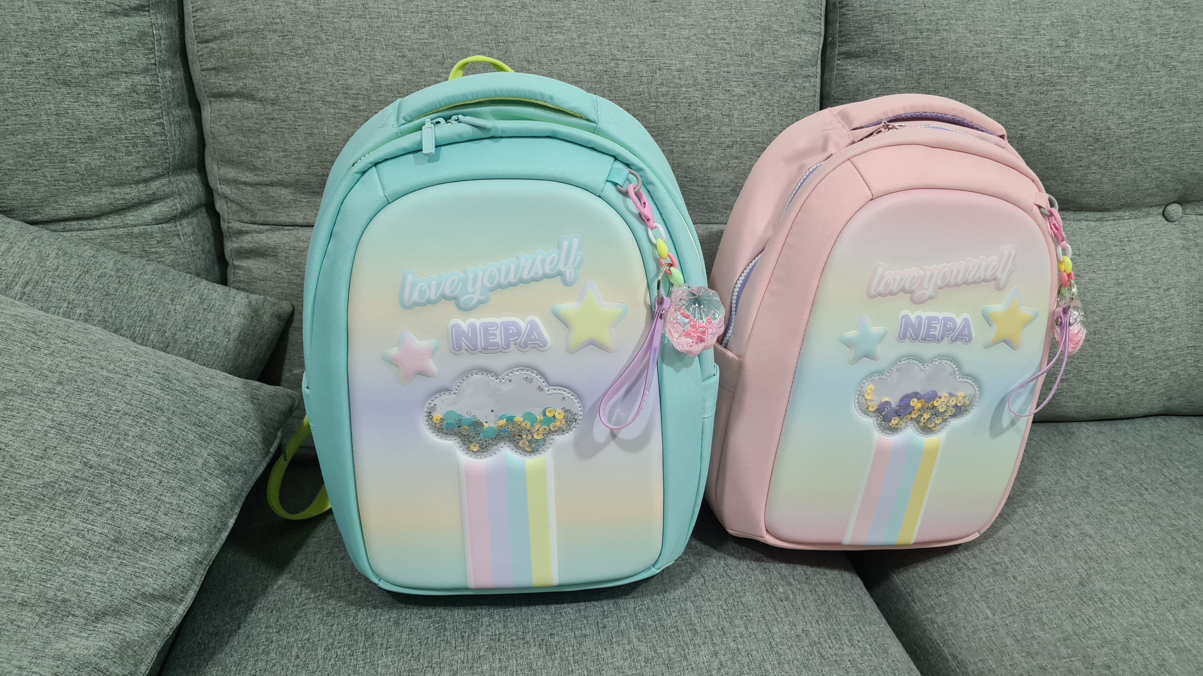 소파위에서 찍은 민트,핑크 색상의 네파 키즈 가방 전면부