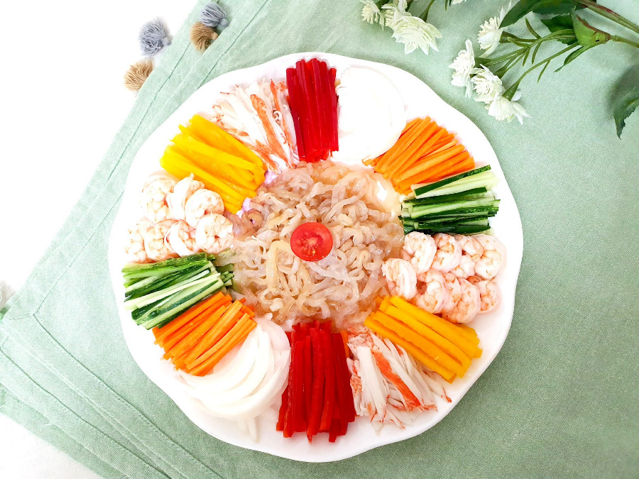 하얗고 동그란 그릇에 당근과 오이, 새우, 고추, 맛살, 해파리 냉채 등을 얇게 썰어 놓고 위에서 찍은 사진