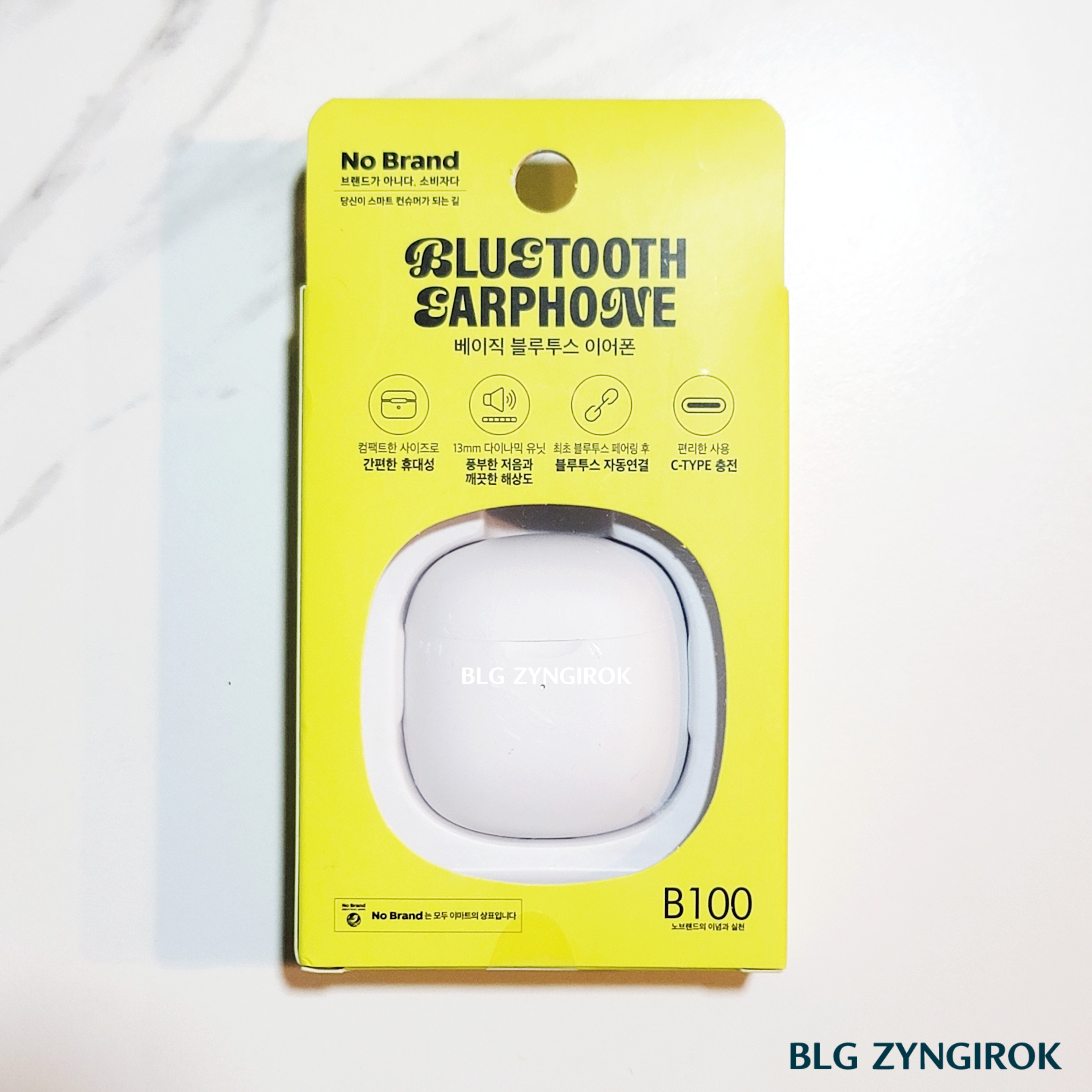 노브랜드 전자기기 : 무선 이어폰 상자가 테이블 위에 놓여있다.