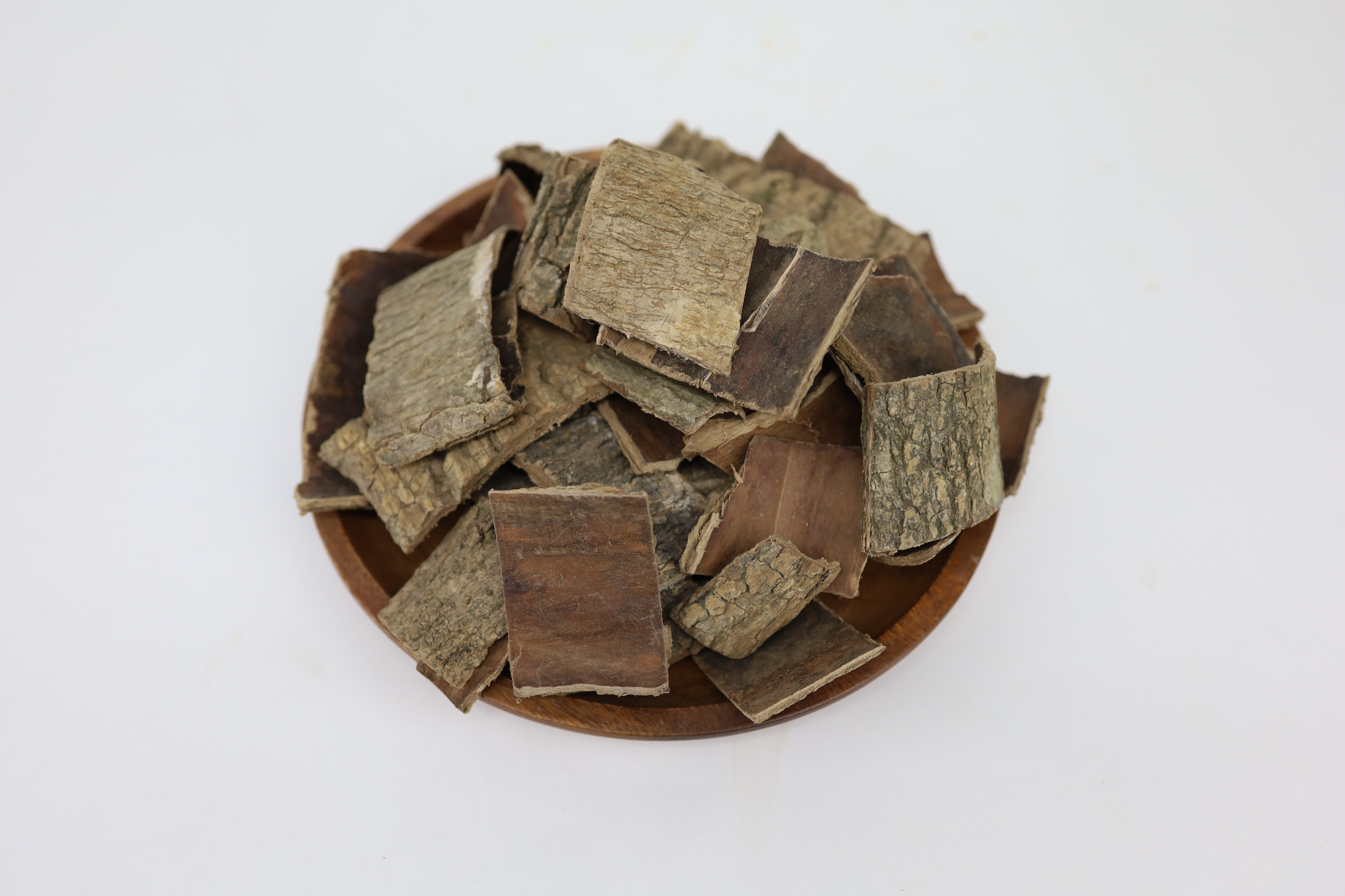 두충 나무에서 껍질을 벗겨, 잘 세척을 한 후에, 잘 건조를 하여 네모난 크기로 잘라서 나무 그릇에 가득 담아 놓은 사진