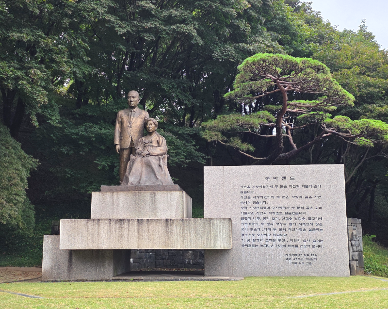 남자와 여자 동상. 남자는 서 있고 여자는 한복을 입고 앉아 있다.
