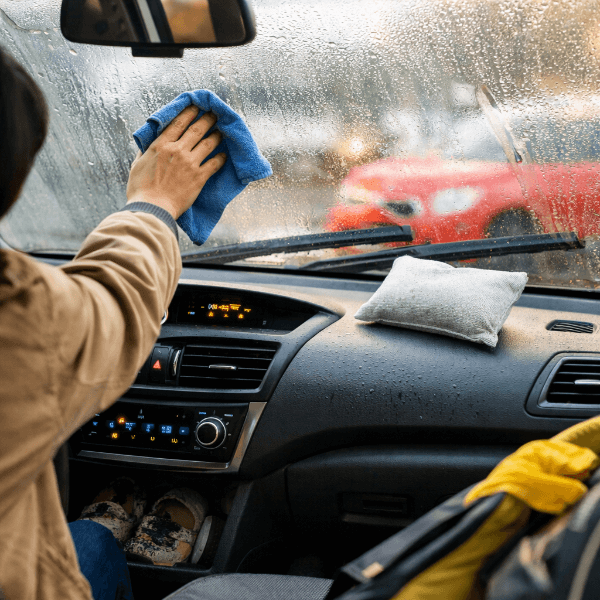 차량 실내 습기로 김서림이 생긴 앞유리를 닦는 모습