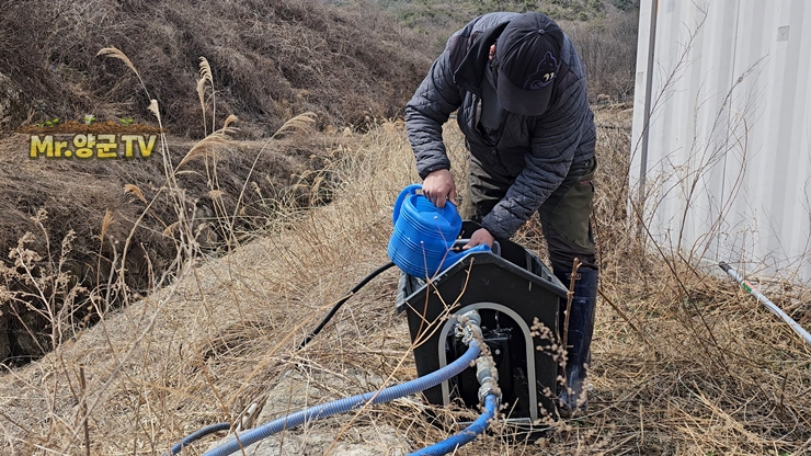 양수기를 작동하기 전 물을 부어 준비하는 모습입니다. 겨울이 지난 뒤 주말농장에 다시 물을 공급하기 위해 양수기와 호스를 연결하고 있습니다.